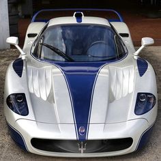 a white and blue sports car parked in front of a garage