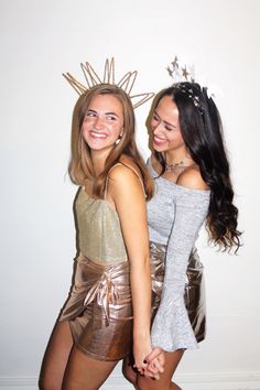 two young women dressed in gold and silver posing for the camera with their hands on each other's hips