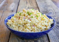 a blue bowl filled with macaroni salad on top of a wooden table