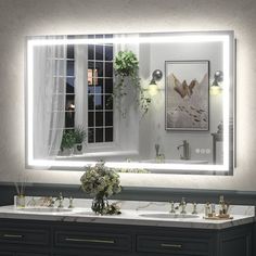 a bathroom vanity with two sinks and a large mirror above it that is lit up