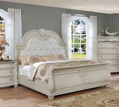 a white bed sitting on top of a wooden floor next to a dresser and mirror