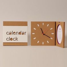 a cardboard box with a clock inside and a calendar on the outside, sitting next to it