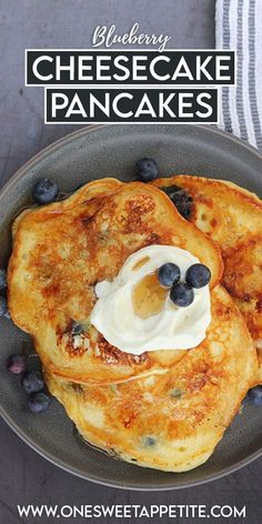 blueberry cheesecake pancakes on a plate with whipped cream and blueberries in the background