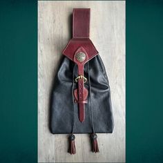 a black and red purse sitting on top of a wooden floor next to a green wall