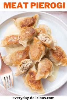 a white plate topped with dumplings next to a fork