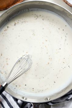 a pan filled with batter and whisk on top of a towel next to a wooden spoon