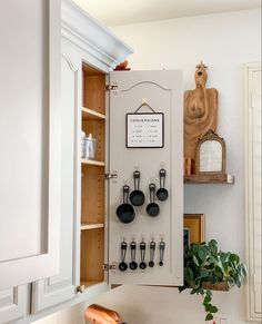 a kitchen with white cabinets and black utensils hanging on the wall above it