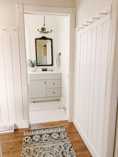 a bathroom with white walls and wood floors