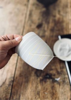 a person holding a coffee cup over a wooden table