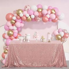 a table with pink, white and gold balloons on it