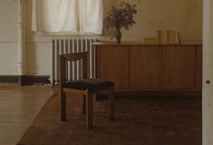 an empty room with a chair next to a window and a radiator on the wall