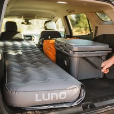 the back end of a van with an inflatable bed and coolers inside