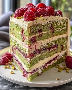 a layered cake with raspberries and pistachios on the top layer