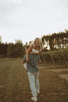 a woman carrying a child in the middle of a field