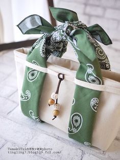 a green and white bag with a bow on it's handle sitting on a table