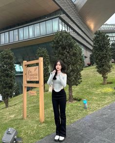 a woman standing next to a sign in front of a building