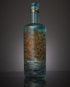 a bottle of blue liquid sitting on top of a black table next to a gray wall