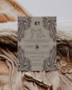 the wedding stationery is laid out on top of a furnishing area with two gold coins