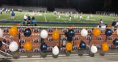 a group of people standing on top of a soccer field next to a fence covered in balloons