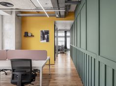 an office with yellow walls and green partitions on the wall, along with two desks