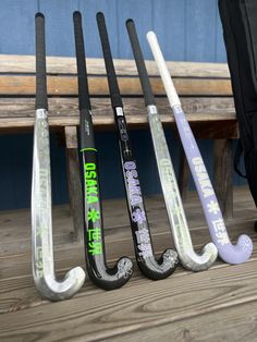 four hockey sticks lined up next to each other on a wooden bench in front of a blue wall