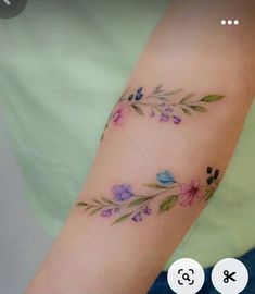 a woman's arm with flowers and leaves tattooed on the left side of her arm