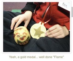 a person sitting on the floor with two small ornaments in front of their face and hands