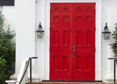 a red door is on the side of a white building with steps leading up to it