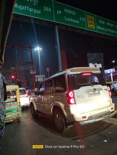 several cars are stopped at an intersection in india, with the lights on and signs above them