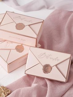 two pink envelopes with gold coins are on top of a pink sheeted bed