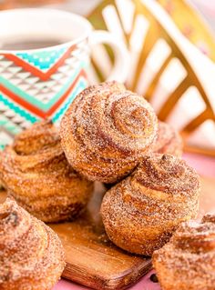 cinnamon rolls on a cutting board next to a cup of coffee