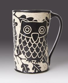 a black and white mug with an owl on it's side, sitting in front of a gray background