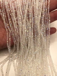 someone is holding some white beads in their left hand and the beading has been sequinized