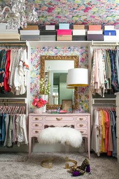 an organized closet with clothes, shoes and a chandelier hanging from the ceiling