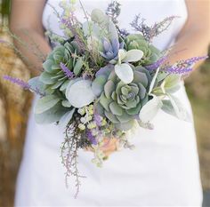 a bride holding a bouquet of succulents and greenery