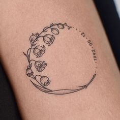 a woman's thigh with a tattoo on it that has flowers in the shape of a crescent