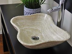 a white sink sitting on top of a black counter next to a potted plant