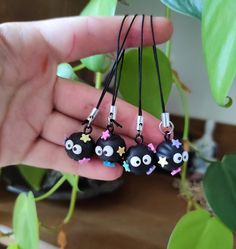 a hand holding three black beads with eyes and stars hanging from it's end