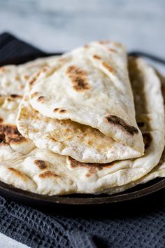 some tortillas are stacked on top of each other in a black plate, ready to be eaten