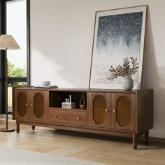 a living room with a large painting on the wall next to a wooden entertainment center