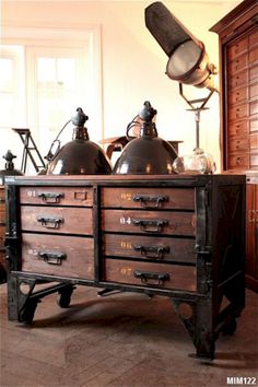 an old dresser has two large metal lamps on it's top and is sitting in front of a window