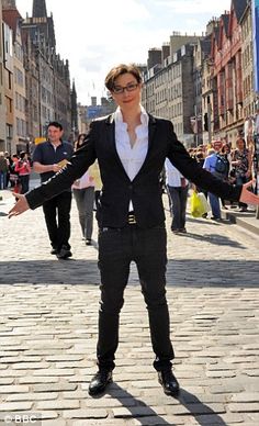 a woman standing in the middle of a street with her arms out and hands outstretched