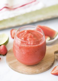 two glasses filled with watermelon and limeade on a wooden tray next to each other