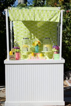 an outdoor ice cream stand with flowers on the table and other items in front of it