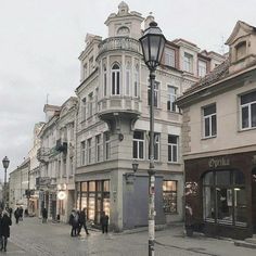 people are walking down the street in front of buildings