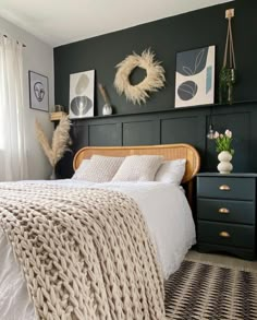 a bedroom with green walls, white bedding and wicker furniture in the corner