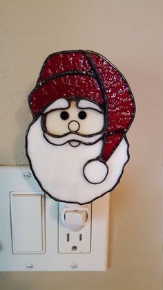 a light switch with a santa claus face on it's side and a red hat hanging from the wall