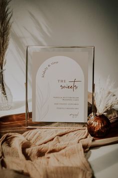 a card and gifts sitting on top of a table next to a vase with dried grass