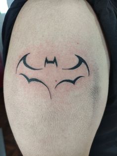 a batman tattoo on the back of a man's left arm, with two bats drawn