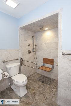 a bathroom with a toilet, sink and shower head mounted to the side of the wall